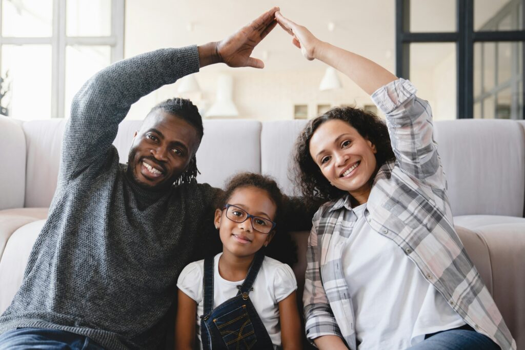 Homeowners, mortgage loan, real estate. Parents making home gesture with hands covering daughter